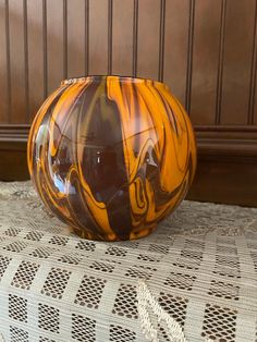 an orange and black vase sitting on top of a table