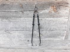 a pair of scissors hanging from the side of a wooden wall with black cord attached to it