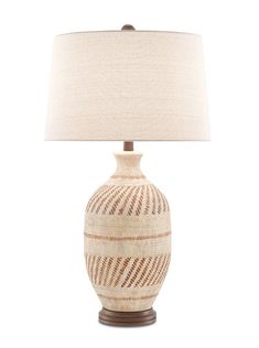 a white and brown vase with a beige shade on it's side, sitting next to a lamp