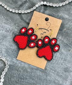 two red and black beaded dog paw earrings on a card with a chain necklace