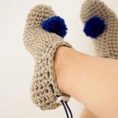 someone is wearing crocheted mittens with blue pom - poms on their feet