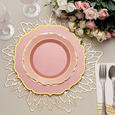 a pink and gold place setting with silverware, flowers and napkins on the table