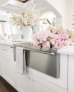 a kitchen with white cabinets and pink flowers