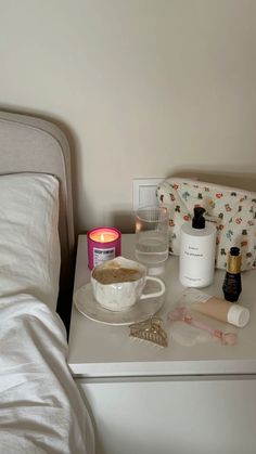 a white table topped with lots of items on top of a bed next to a night stand