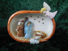 the nativity scene is displayed in an orange bowl on green velvet background with stars