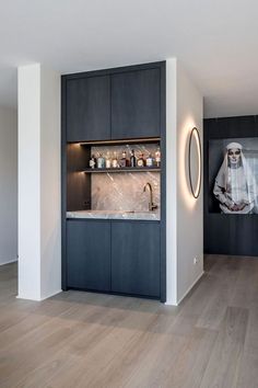 a modern kitchen with wood floors and black cabinetry, lighted by recessed lights