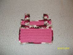 a pink crocheted purse sitting on top of a white floor next to a wall