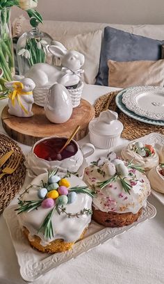 a table topped with cakes and cupcakes covered in frosting next to flowers