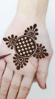 a woman's hand with a hendi on it and a pen in the other hand