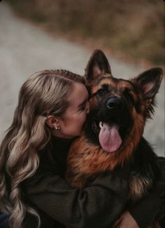 a woman is hugging her german shepherd dog