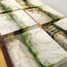 several square pieces of marble sitting on top of a wooden table next to each other