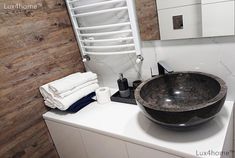 a black bowl sink sitting on top of a white counter next to a towel rack