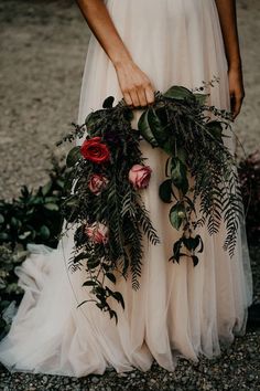 a woman in a white dress holding flowers and greenery