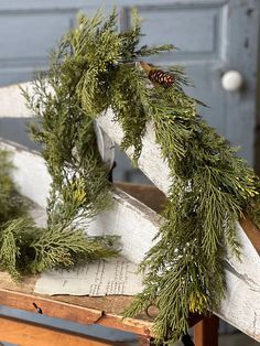 a wooden sled filled with evergreen branches and pine cones sitting on top of an old book