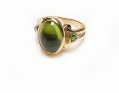 Kurt Wayne Ring.Vintage Kurt Wayne 18K yellow gold ring set with a cabochon peridot and two tsavorite. Classic Green Multi-stone Sapphire Ring, Green Gemstone Cabochons Fine Jewelry, Green Oval Cabochons Fine Jewelry, Oval Green Sapphire Ring Hallmarked, Tsavorite Ring, Genuine Love, Gold Ring Sets, 18k Yellow Gold Ring, Yellow Gold Ring