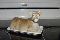 a ceramic cow sitting on top of an oven