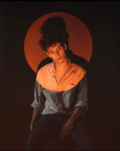 a man sitting on top of a stool in front of a red and black background