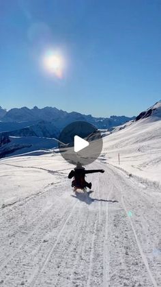 a person riding skis on top of a snow covered slope with mountains in the background