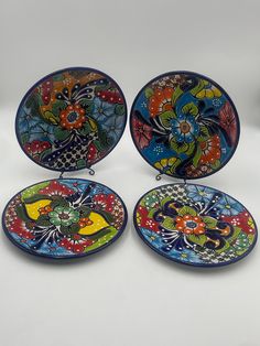 four colorful plates with designs on them are sitting next to each other and one is empty