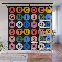 a colorful alphabet wall mural in a living room with a ladder and chair next to it