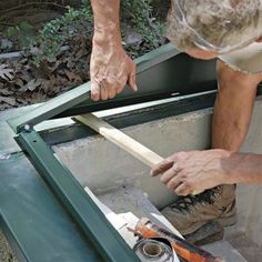 two men working on something in the back of a green box with tools inside it