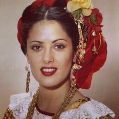 a woman with a flower in her hair wearing gold jewelry and a red head piece