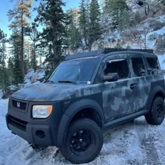 an suv is parked in the snow near some trees