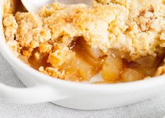 an apple cobbler in a white bowl with a spoon