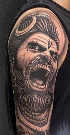 a man's arm with an evil face and demon head on it, in black and grey