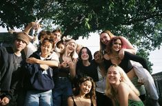 a group of young people standing next to each other in front of a large tree