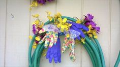 a wreath with flowers and gardening gloves hanging from it