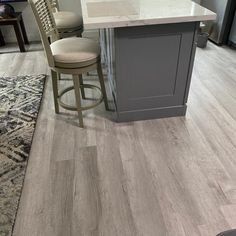 a kitchen with an island and stools next to a rug on the hardwood floor