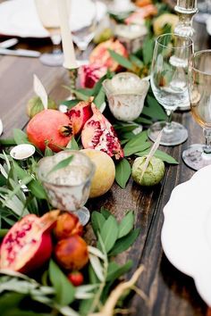 the table is set with fruit and greenery for a festive dinner or party