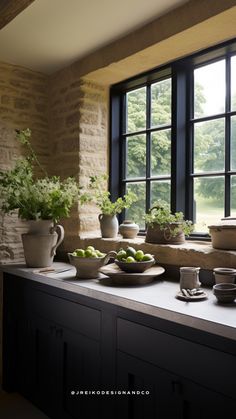 a kitchen counter topped with plates and bowls filled with fruit next to a large window