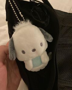 a small stuffed animal is in a black bag with a chain around it's neck