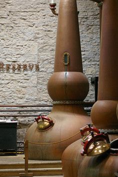 two large brown vases sitting next to each other in front of a brick wall