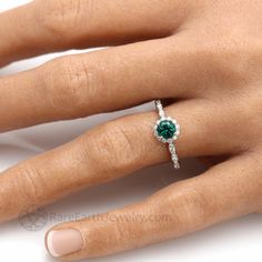 a woman's hand with a ring on it and a green stone in the middle