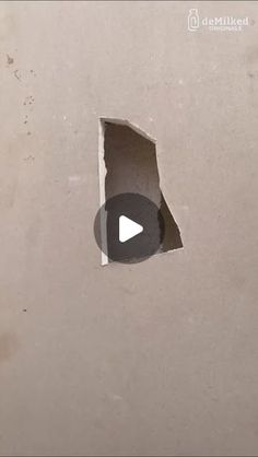 a hole in the side of a wall that has been torn open with a video play button