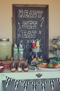 a football themed party with food and drinks on a table in front of a chalkboard