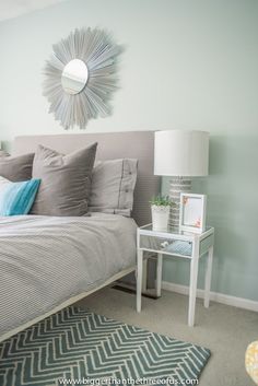 a bed room with a neatly made bed and a mirror on the wall above it