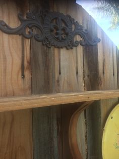 a wooden shelf with a clock on top of it next to a fence and palm tree