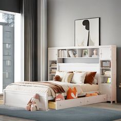 a white bed sitting next to a window with lots of bookshelves on top of it