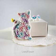 a decorative cat figurine sitting on top of a doily next to a box