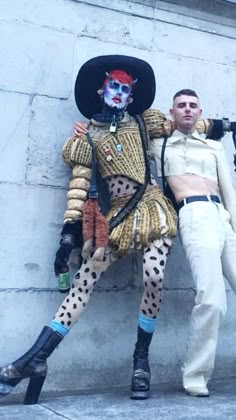 two people dressed up as clowns are posing for a photo in front of a wall