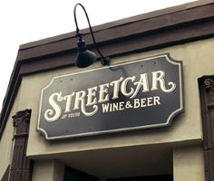 streetcar wine and beer sign hanging from the side of a building with lights on it