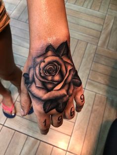 a woman's hand with a black rose tattoo on it and the word love written in cursive letters