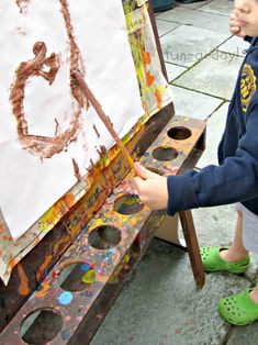 a young boy is painting on an easel