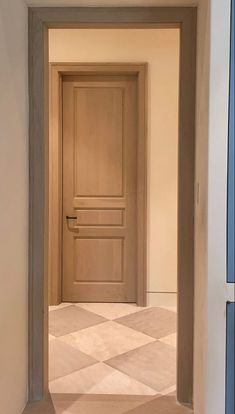 an empty hallway with a wooden door and checkered floor