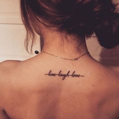 the back of a woman's neck with a tattoo that reads, live laugh love