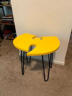 a yellow table with black hairpinks on it in front of a white wall